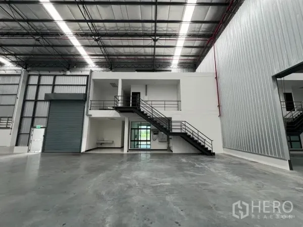 Warehouse for rent in Chon Buri - Internal office block with stairs, mezzanine and a roller shutter door inside the warehouse.