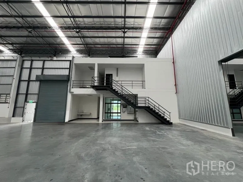 Warehouse for rent in Chon Buri - Internal office block with stairs, mezzanine and a roller shutter door inside the warehouse.
