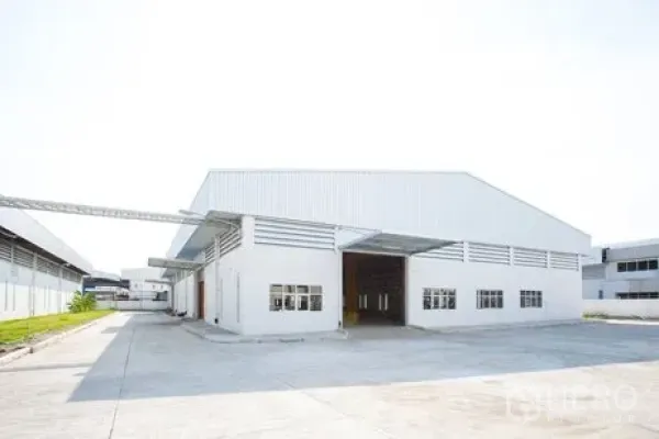 Factory for rent in Bang Pakong, Chachoengsao - Front view of modern white factory warehouse with high gable roof, large roller shutter and truck access.