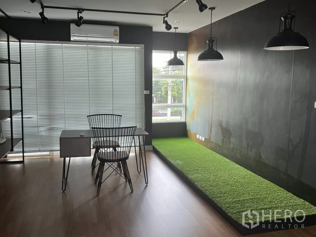 Detached House for rent or sale in Don Mueang, Bangkok - Corner workspace with window blinds, black pendant lights and raised green turf platform.