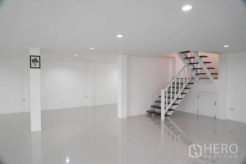 Detached House for sale in Bang Bon, Bangkok - Minimalist white interior space with columns and stairway to the upper level.