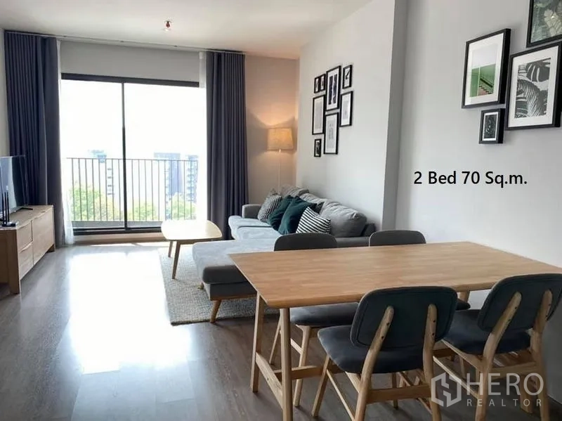 Condominium for rent in Watthana, Bangkok - Open-plan living and dining room with balcony access, sofa set and wall art near Ekkamai BTS.