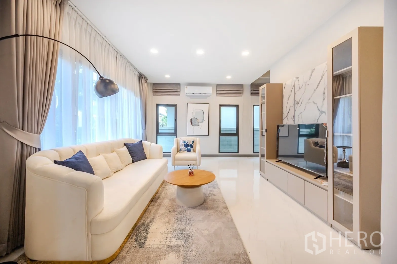 Detached House for rent in Bang Phli, Samut Prakan - Bright living room with large windows, white sofa, TV wall and recessed lighting