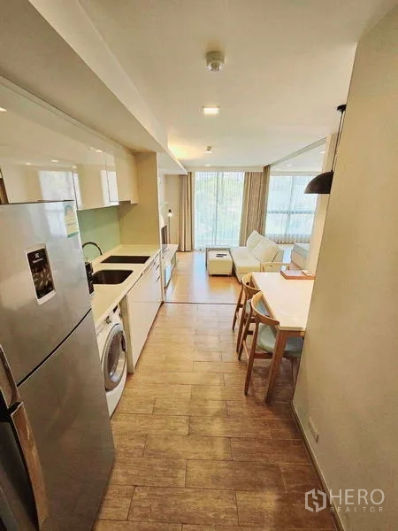 Condominium for rent - Galley kitchen, dining table and lounge aligned toward bright full-height windows.