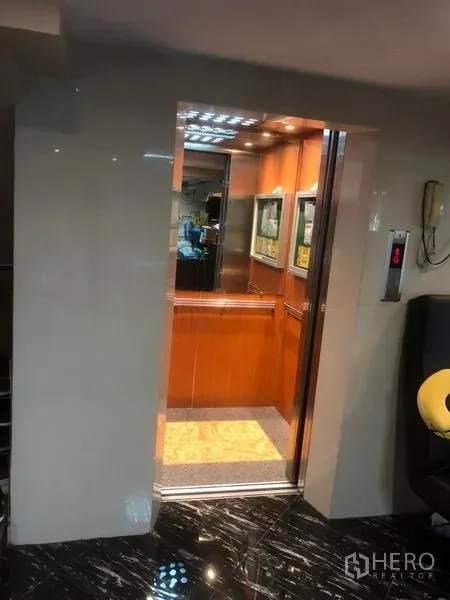 店屋 出租在Bang Rak, Bangkok - 商铺大堂内开启的电梯，木质饰面厢体。