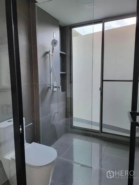 บ้าน ให้เช่าในSaphan Sung, Bangkok - ห้องน้ำกะทัดรัด ปูกระเบื้องสีเทา ฉากกั้นอาบน้ำกระจก และโถสุขภัณฑ์แบบโมเดิร์น