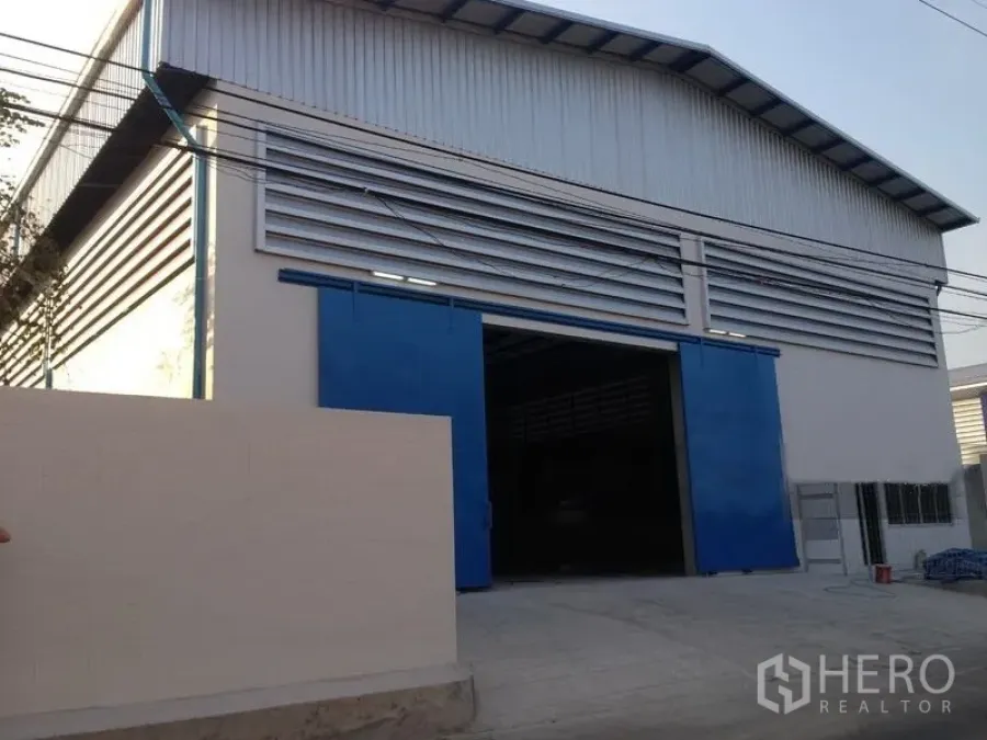 คลังสินค้า ให้เช่าในMueang Samut Prakan, Samut Prakan - ด้านหน้าโกดังกรุเมทัลชีท ประตูเลื่อนสีฟ้าขนาดใหญ่และลานจอด