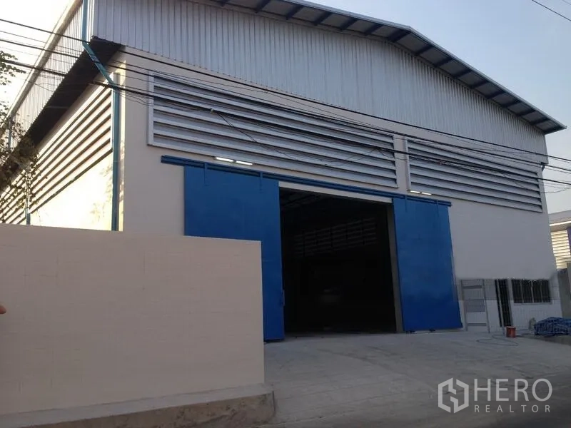 คลังสินค้า ให้เช่าในMueang Samut Prakan, Samut Prakan - ด้านหน้าโกดังกรุเมทัลชีท ประตูเลื่อนสีฟ้าขนาดใหญ่และลานจอด