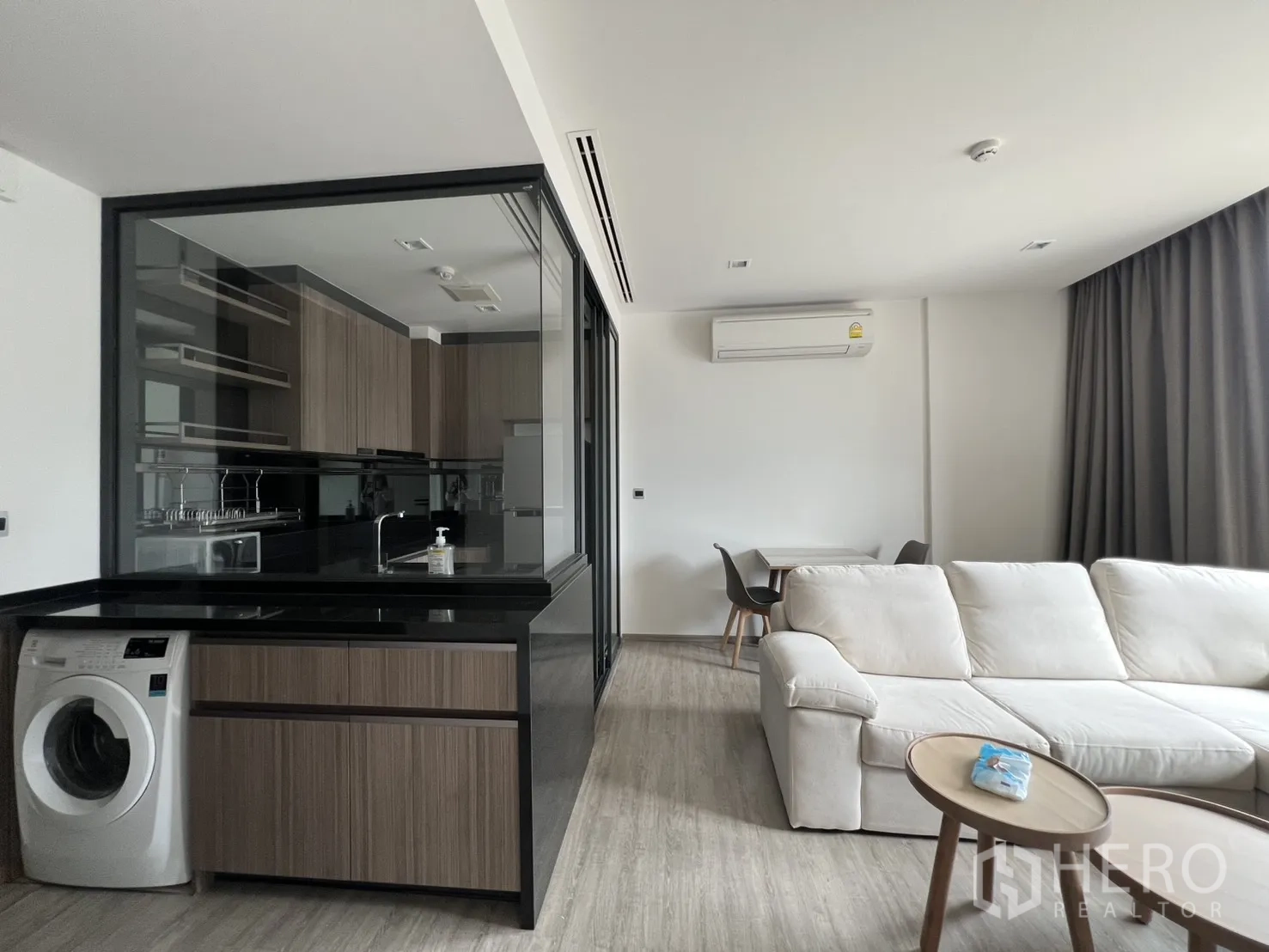 公寓 for rent in Watthana, Bangkok - 宽敞客厅，旁有玻璃墙厨房和小型用餐角，配空调。