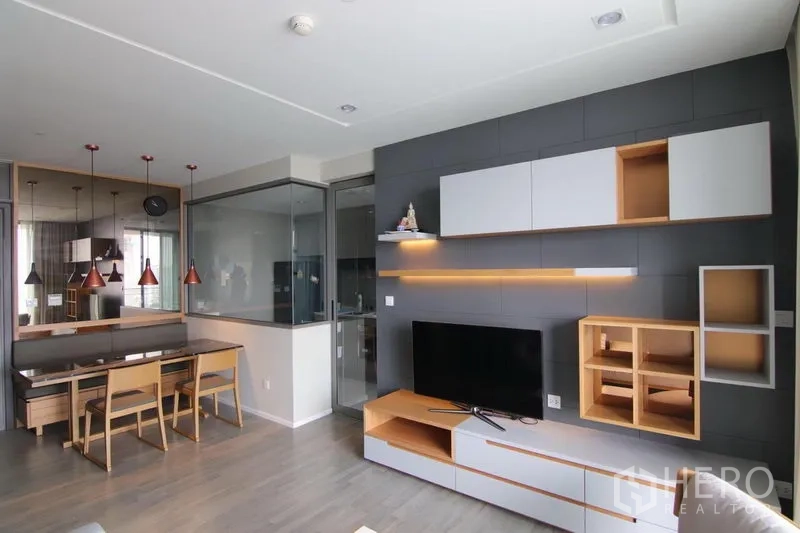 Condominium for rent in Bang Sue, Bangkok - Open-plan lounge facing the dining nook and glass-partitioned kitchen with contemporary media cabinetry.