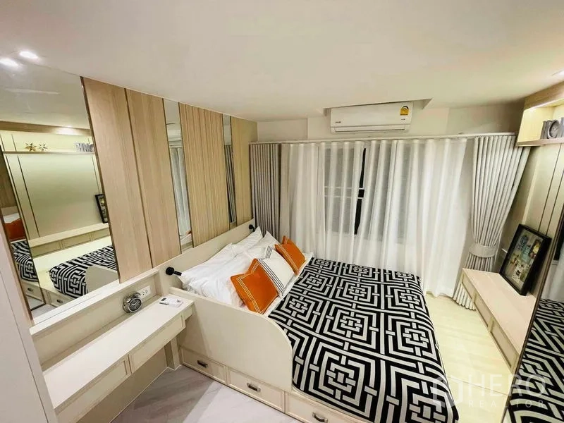 Condominium for sale in Yan Nawa, Bangkok - Bedroom with blackout curtains, air conditioner, and geometric bed cover.