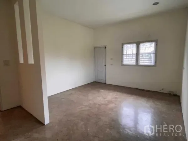 Warehouse for rent in Bang Phli, Samut Prakan - Empty office room with white walls, barred window and a solid door inside the warehouse.