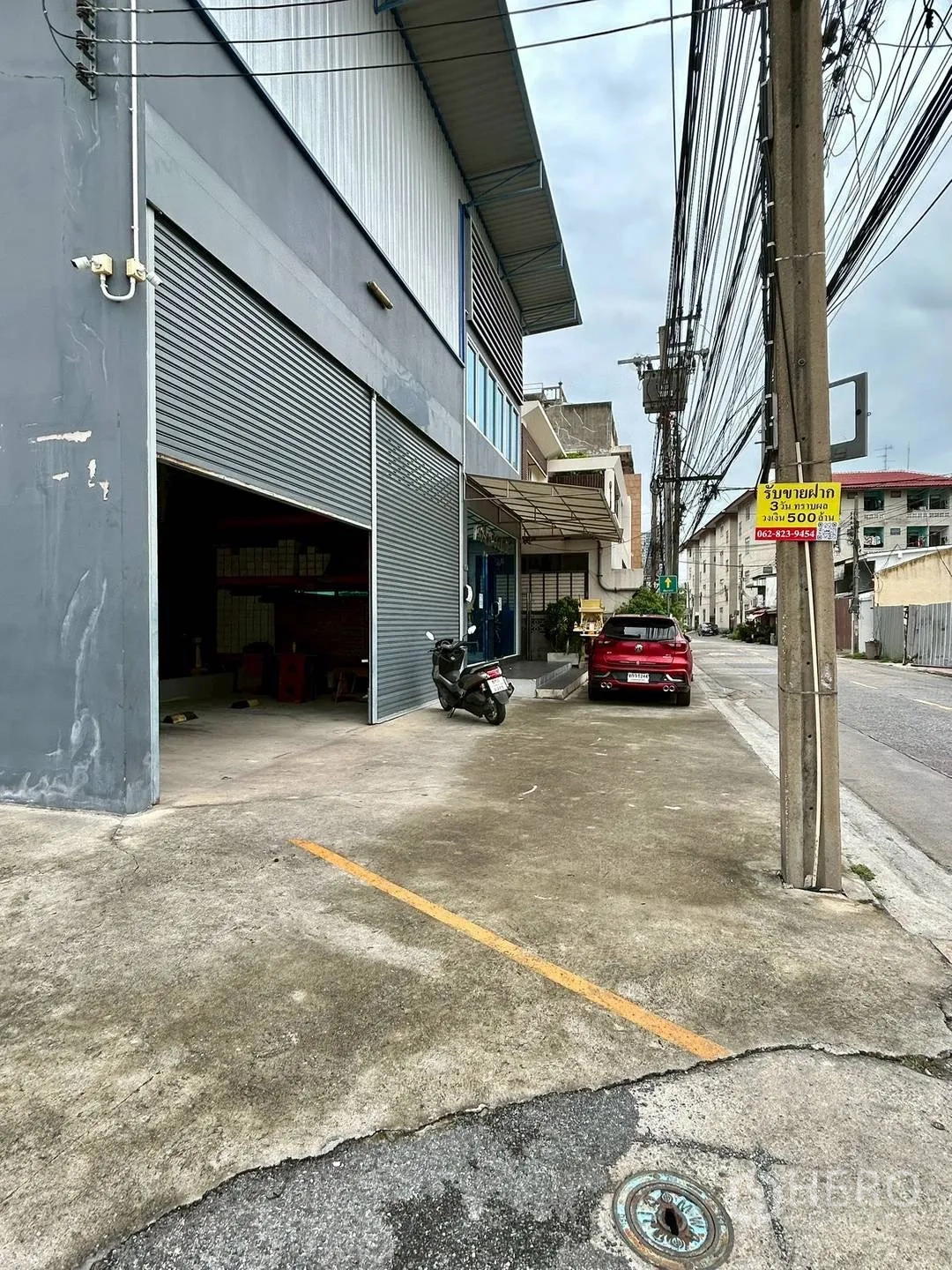 Warehouse for rent in Suan Luang, Bangkok - Front parking strip and open shutter providing vehicle access to the bay.