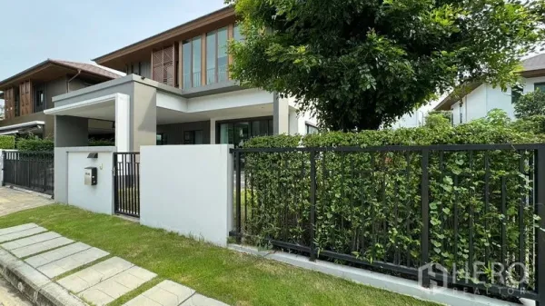 Detached House for rent in Prawet, Bangkok - Modern two-storey detached house with front gate, hedge and driveway.