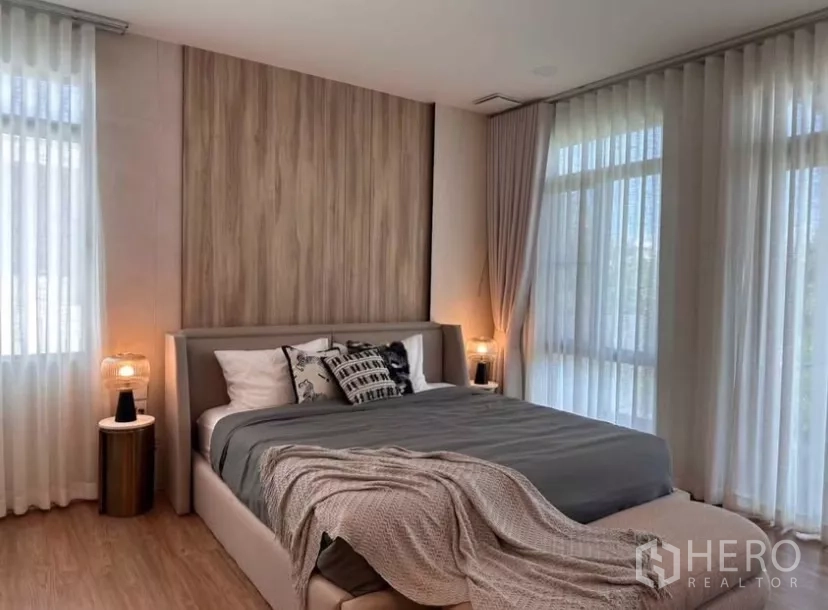Detached House for rent in Samut Prakan - Primary bedroom with wood headboard, bedside lamps, and wraparound curtains.