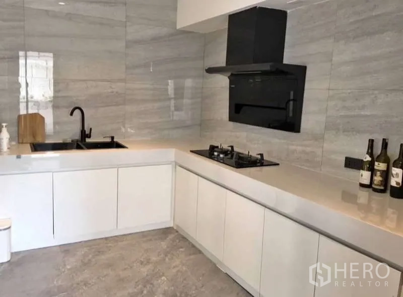 联排别墅 出租或出售在Prawet, Bangkok - L形现代厨房，白色橱柜、燃气灶与黑色烟机