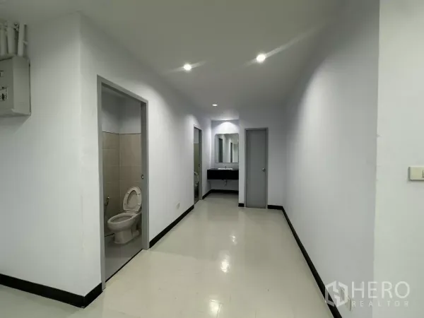 Office Space for rent - In‑unit restroom corridor with two toilet rooms and a shared vanity sink.