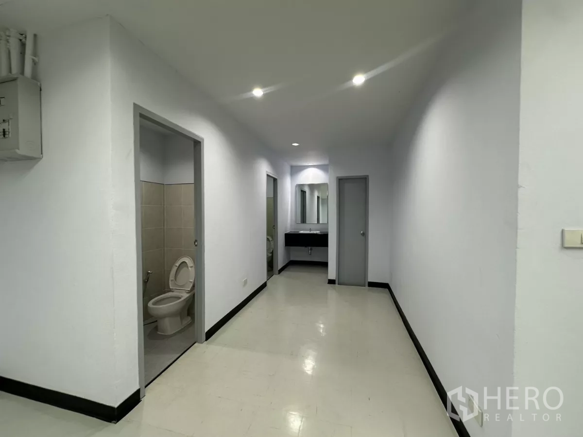 Office Space for rent - In‑unit restroom corridor with two toilet rooms and a shared vanity sink.