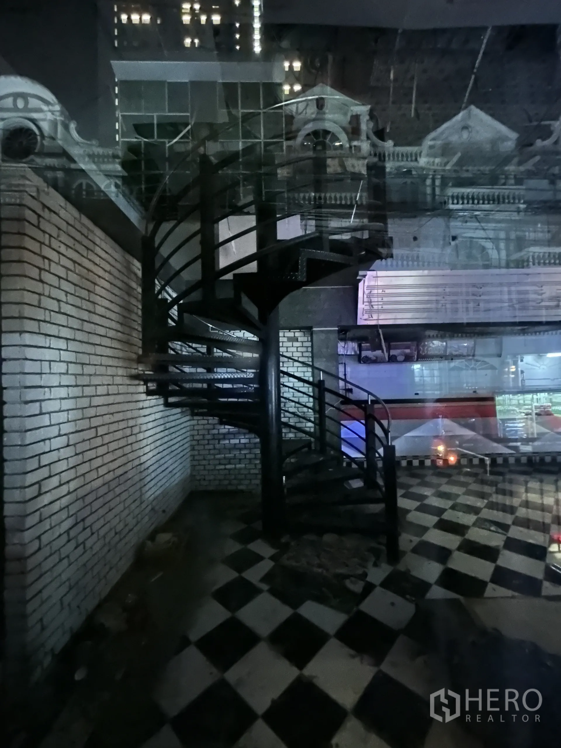 พื้นที่ขายปลีก ให้เช่าในWatthana, Bangkok - บันไดเวียนข้างผนังก่ออิฐสีขาวบนพื้นลายตาราง พร้อมเงาสะท้อนแสงเมืองบนกระจก