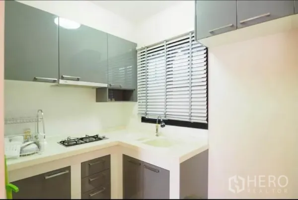 ทาวน์เฮาส์ ให้เช่าหรือขายในWang Thonglang, Bangkok - ครัวรูปตัว U ขนาดกะทัดรัด ตู้ลายเงาสีเทา เตาแก๊ส อ่างล้างจาน และมู่ลี่หน้าต่าง