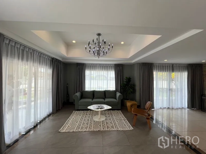 Detached House for sale in Mueang Pathum Thani, Pathum Thani - Formal living room with chandelier ceiling, sheer curtains and sofa set.