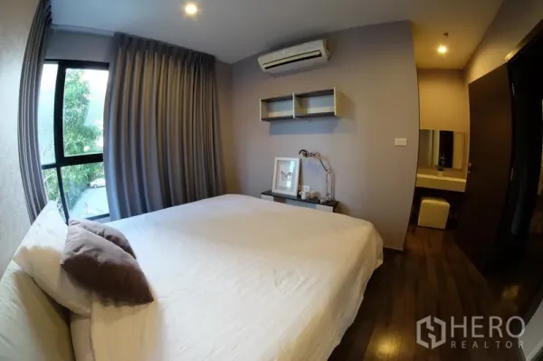 公寓 出租在Watthana, Bangkok - 主卧配壁挂收纳与梳妆区，空调齐全，窗外可见树景。