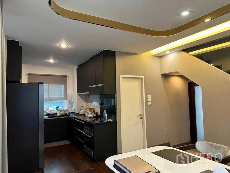 Detached House for sale in Suan Luang, Bangkok - Modern kitchen with black cabinetry next to the dining area and stair lighting.