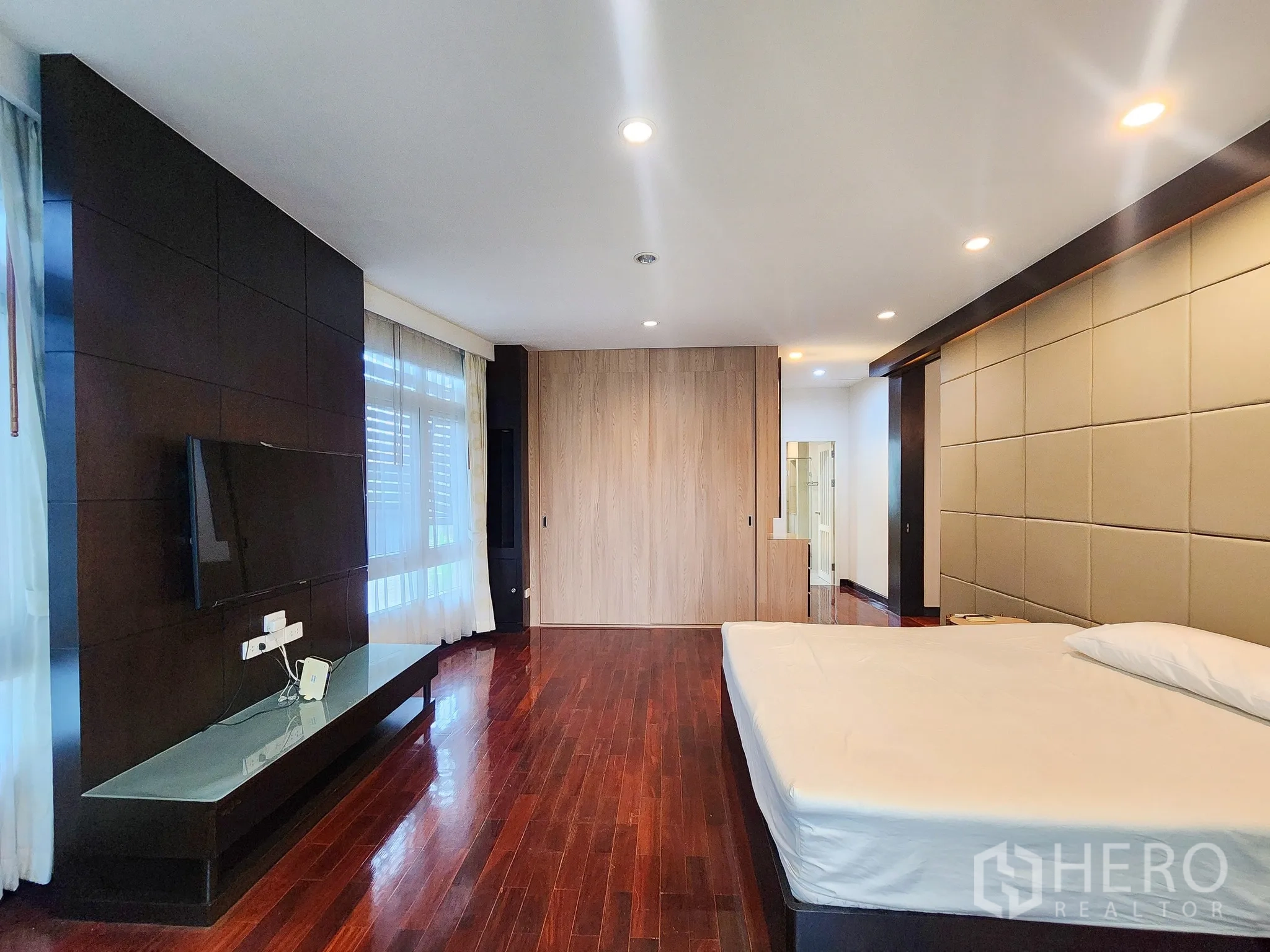 独立式住宅 出租在Bang Kapi, Bangkok - 宽敞主卧，电视墙、抛光木地板与大窗户。