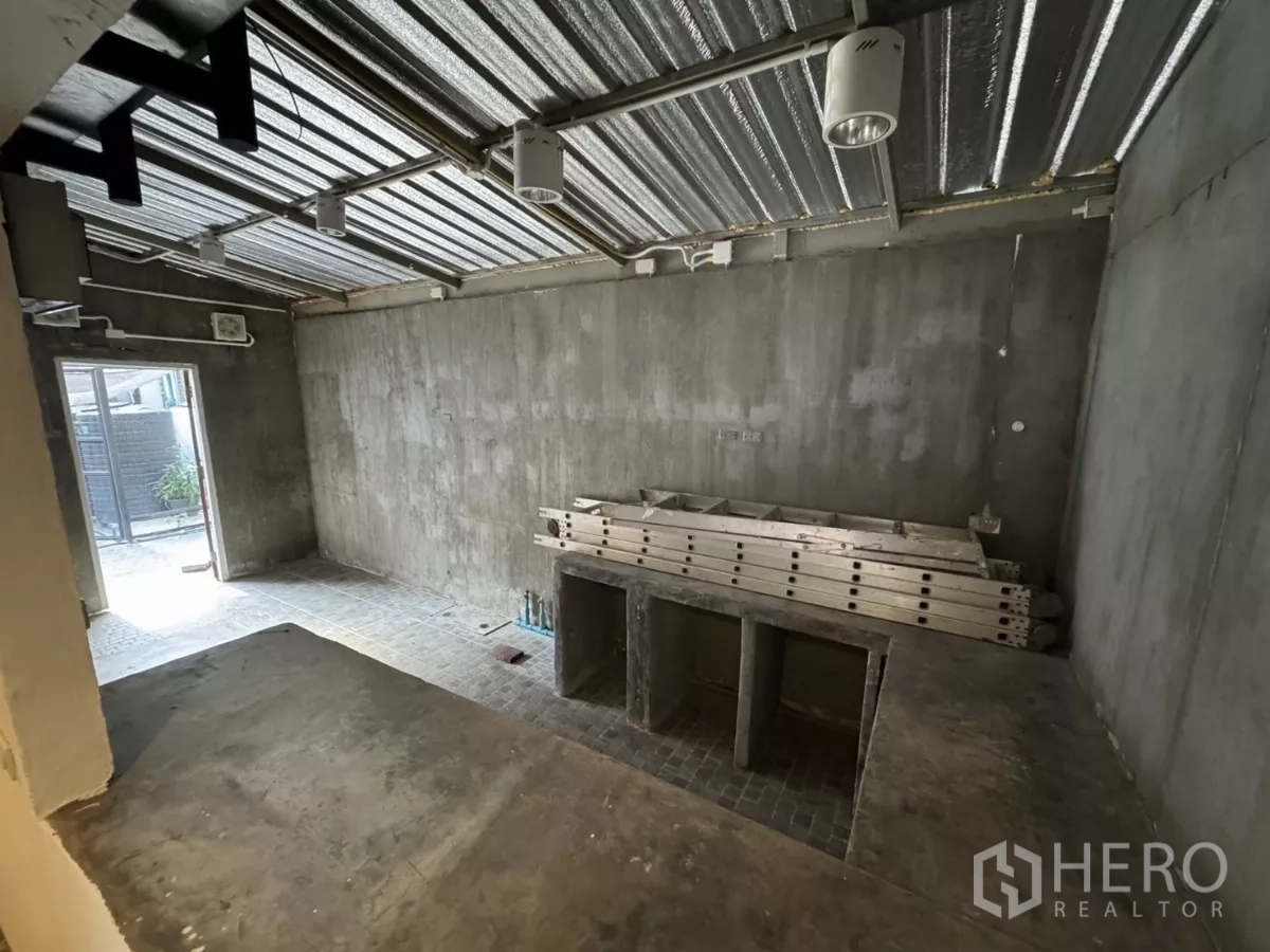 店屋 出租在Wang Thonglang, Bangkok - 一层后场，未完成的水泥墙、金属屋顶与工作台。