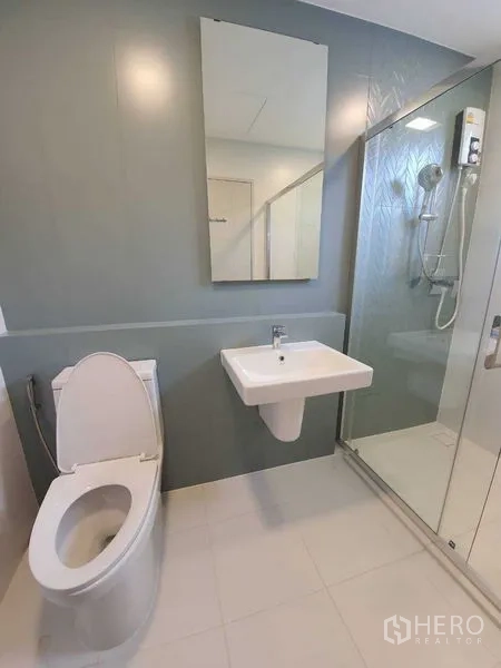Townhouse for rent - Contemporary bathroom with glass-enclosed shower, wall mirror, sink, and toilet.
