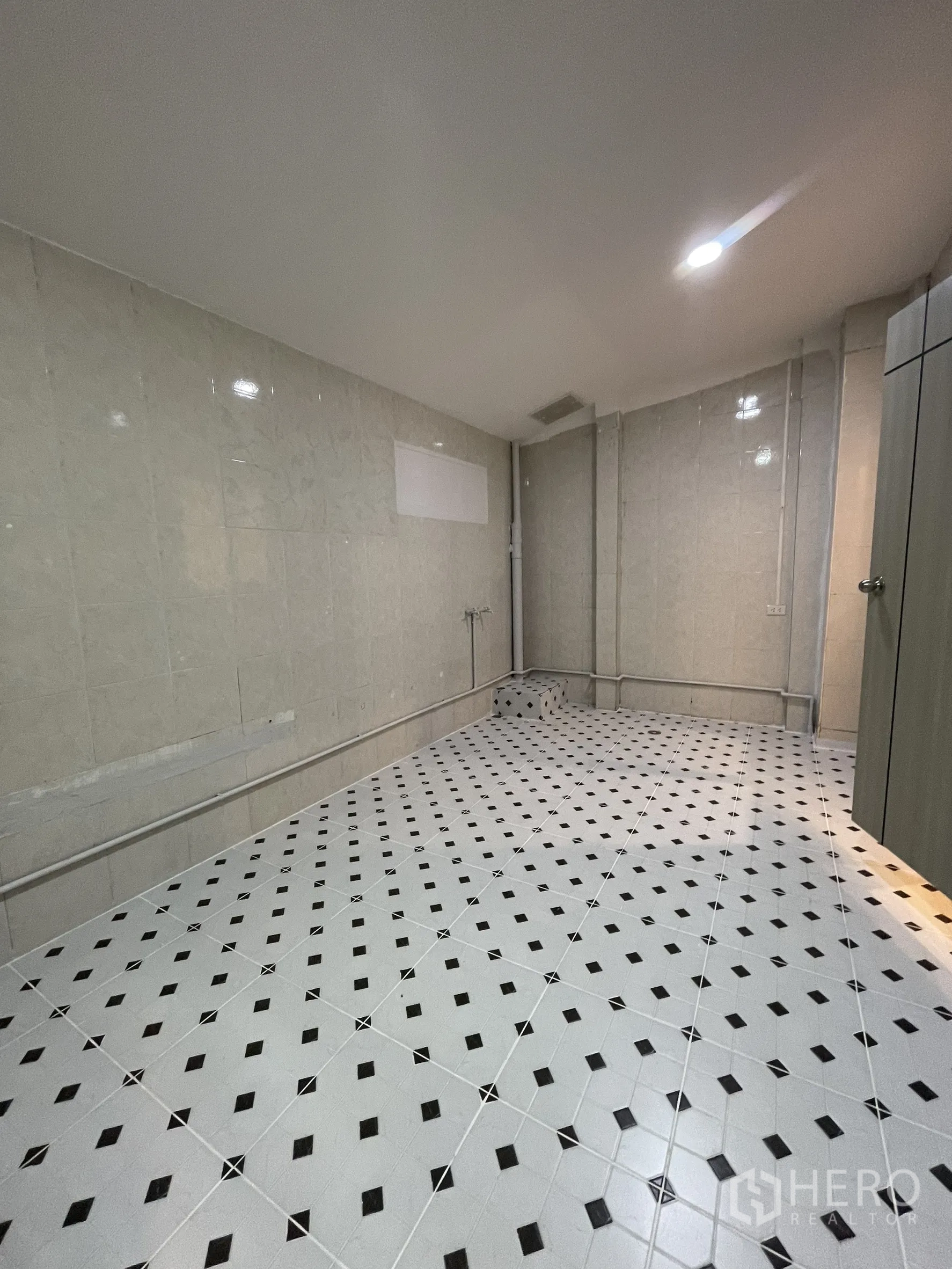 Shophouse for rent in Bang Kapi, Bangkok - Tiled utility or storage room with white floor and black diamond pattern under recessed lighting.