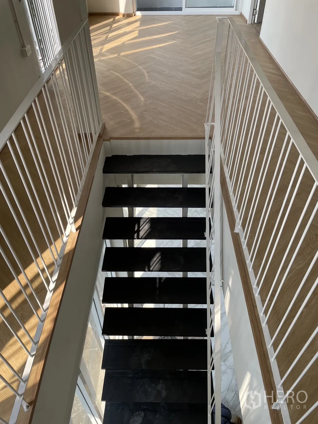 บ้าน ให้เช่าหรือขายในDin Daeng, Bangkok - มุมมองบันไดขั้นสีดำ ราวเหล็กสีขาวลงสู่ชั้นล่าง