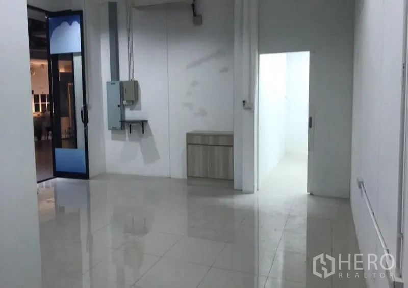 办公空间 出租在Watthana, Bangkok - 白色办公内部，亮面瓷砖地、配电箱以及通往后室的门。