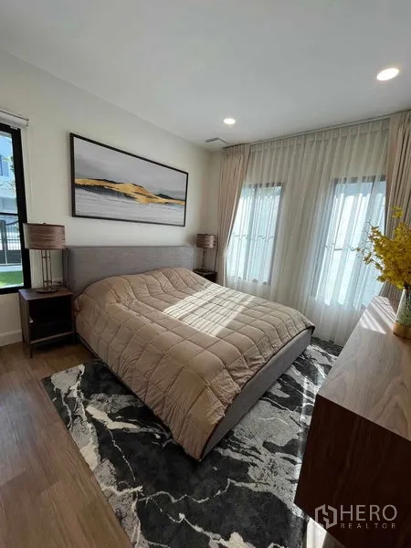 Detached House for rent in Saphan Sung, Bangkok - Cozy bedroom with double bed, wooden dresser, two windows and soft natural light.