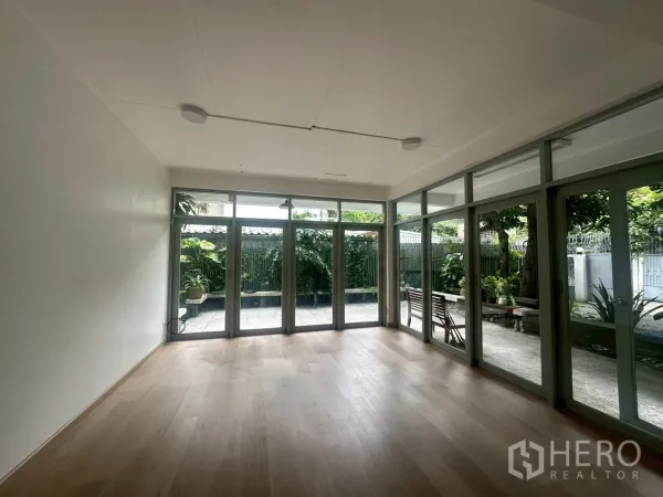 บ้าน ให้เช่าในWatthana, Bangkok - ห้องนั่งเล่นโปร่งสว่าง พื้นไม้โทนอ่อน ประตูกระจกสูงจรดเพดานเปิดออกสู่เฉลียง.