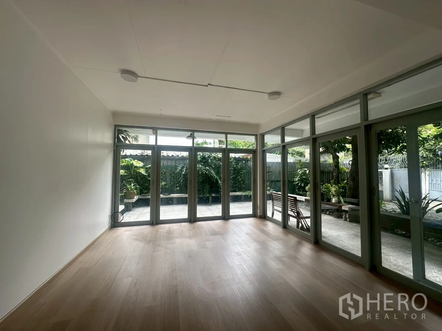 บ้าน ให้เช่าในWatthana, Bangkok - ห้องนั่งเล่นโปร่งสว่าง พื้นไม้โทนอ่อน ประตูกระจกสูงจรดเพดานเปิดออกสู่เฉลียง.