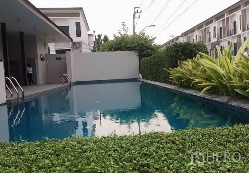 Townhouse for rent or sale in Bang Kapi, Bangkok - Resident swimming pool bordered by hedges and low-rise townhouses within the estate.
