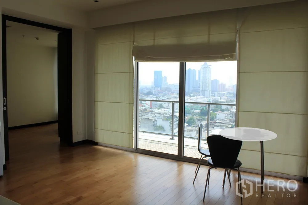 Condominium for rent or sale in Yan Nawa, Bangkok - Bright living area with hardwood floors opening to a balcony and skyline view through floor-to-ceiling windows.