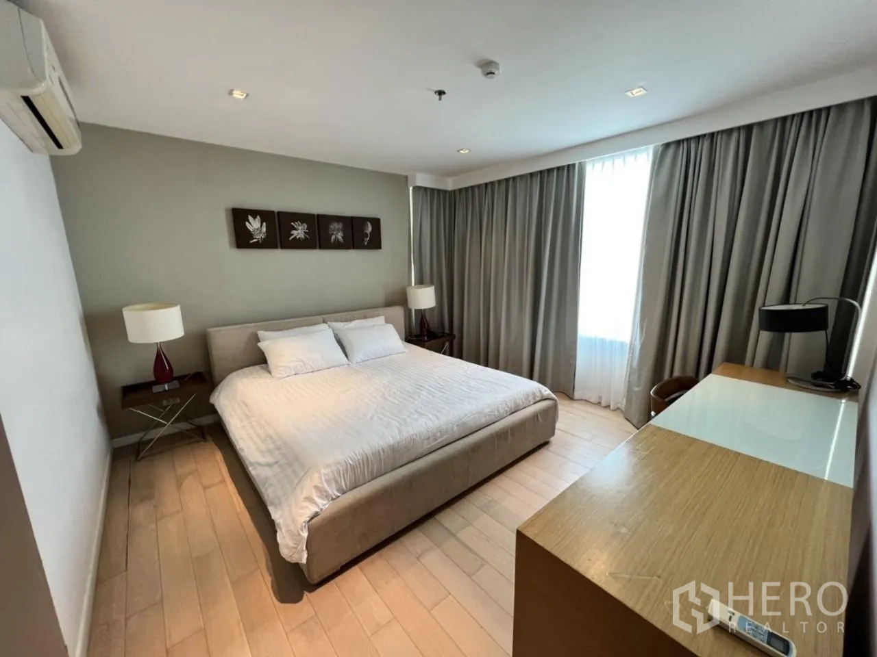 公寓 出租在Watthana, Bangkok - 主卧配特大床、床头灯、木地板与靠窗书桌。