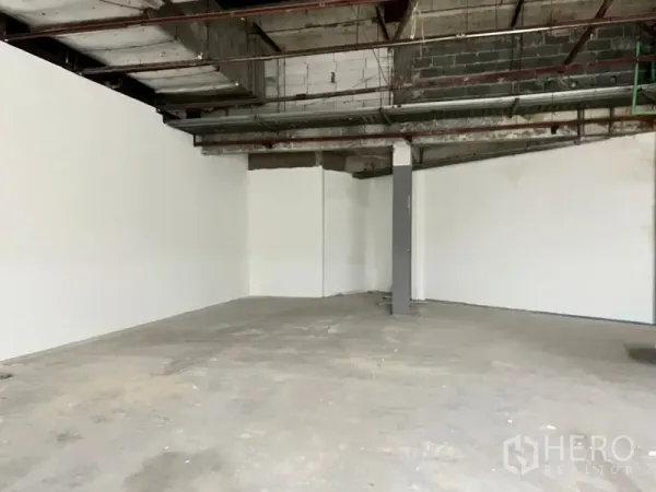 零售空间 出租在Khlong Toei, Bangkok - 白色围墙、大型零售区与中央立柱，天花为开放式。