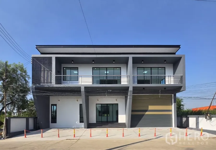 货栈 出售在Lam Luk Ka, Pathum Thani - 现代两层办公室立面与仓库，设阳台、宽幅卷闸门和混凝土装卸区。