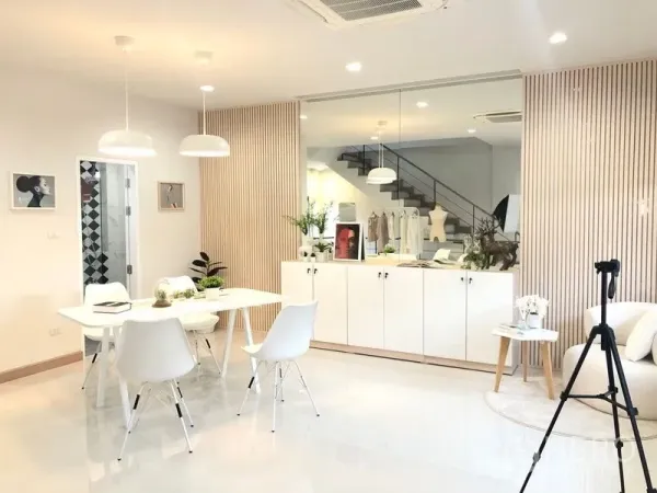 Shophouse for rent in Lat Phrao, Bangkok - Minimalist meeting area with pendant lights, built-in cabinet and a mirrored wall beneath recessed lighting.