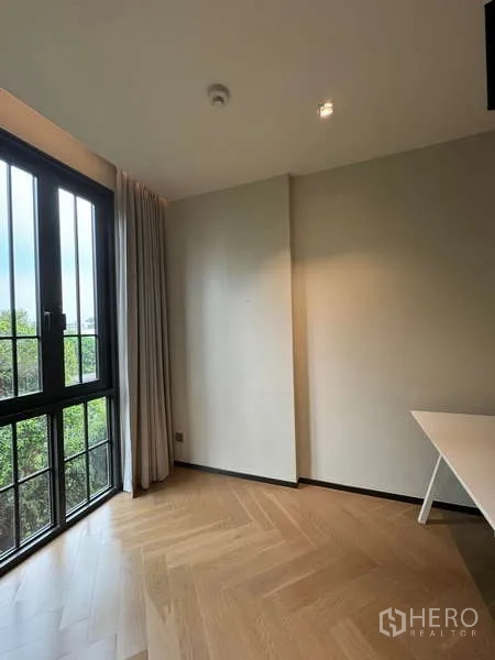 Condominium for rent in Watthana, Bangkok - Corner study nook with desk and large casement window overlooking trees.