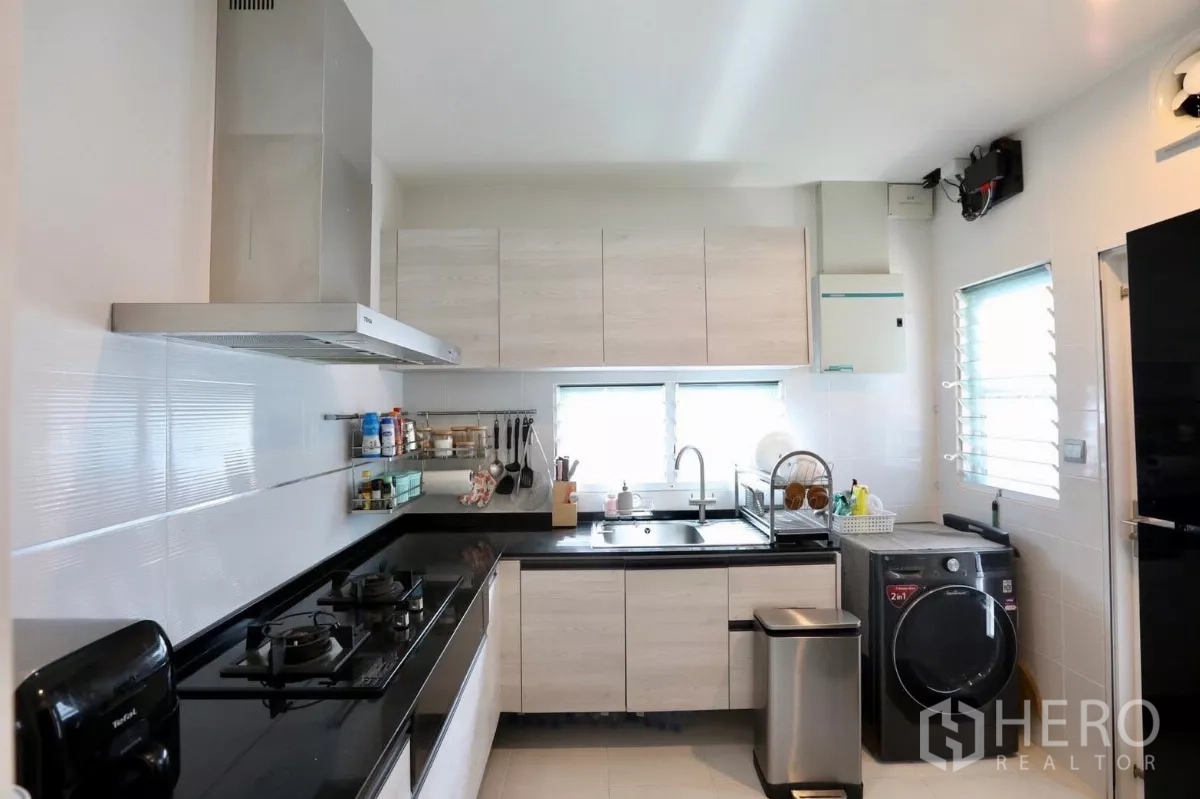 Detached House for rent in Samut Prakan - Built-in pantry with black marble countertop and glass cabinets beside a showcase wall.