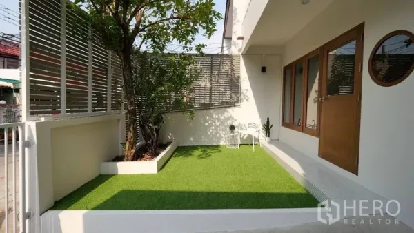 ทาวน์เฮาส์ ให้เช่าในKhlong Toei, Bangkok - สวนหน้าบ้านปูหญ้าเทียม พร้อมระแนงบังสายตา และประตูไม้เข้าสู่ตัวบ้าน
