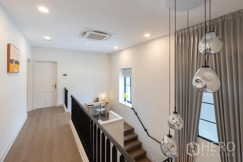 Detached House for sale in Saphan Sung, Bangkok - Stair landing with hanging glass pendant lights and small work desk.