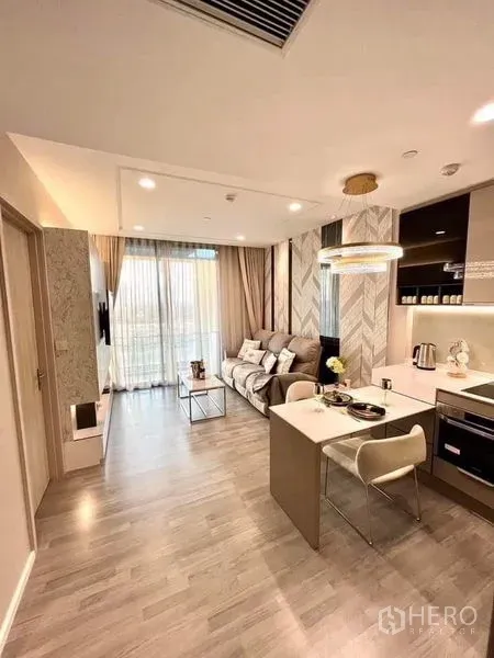 Condominium for sale in Bang Sue, Bangkok - Open kitchen and living space with breakfast bar, pendant lighting and sliding glass doors to balcony.