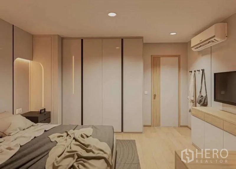 Condominium for rent in Huai Khwang, Bangkok - Primary bedroom with built-in wardrobes, wall-mounted TV and soft ambient lighting.