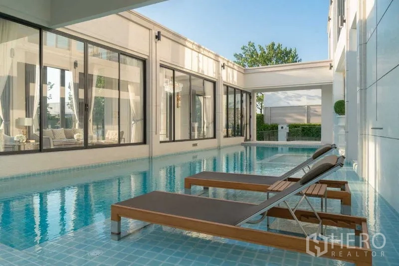 Detached House for sale in Prawet, Bangkok - Clubhouse indoor pool with loungers beside floor-to-ceiling windows.