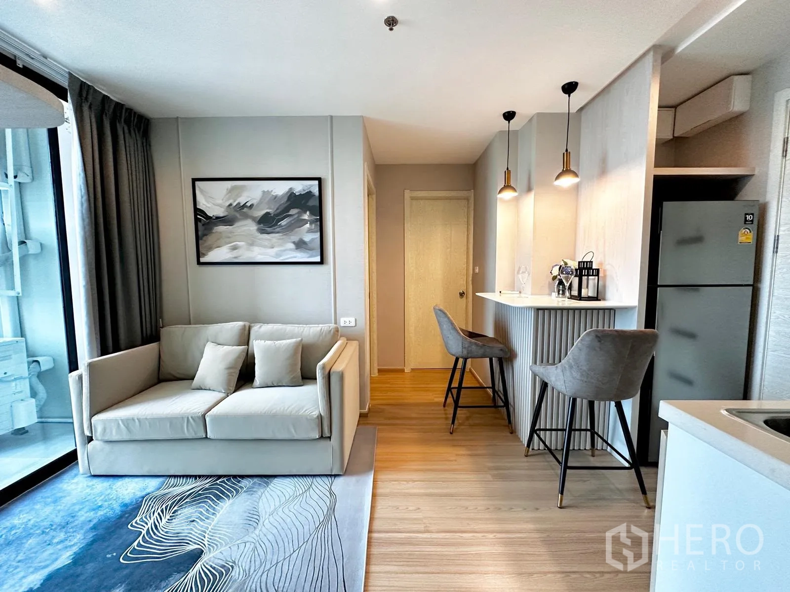 คอนโด for rent in Suan Luang, Bangkok - โซนนั่งเล่นเปิดโล่งมีโซฟา พรม บานกระจกเลื่อน และเคาน์เตอร์บาร์ข้างตู้เย็น